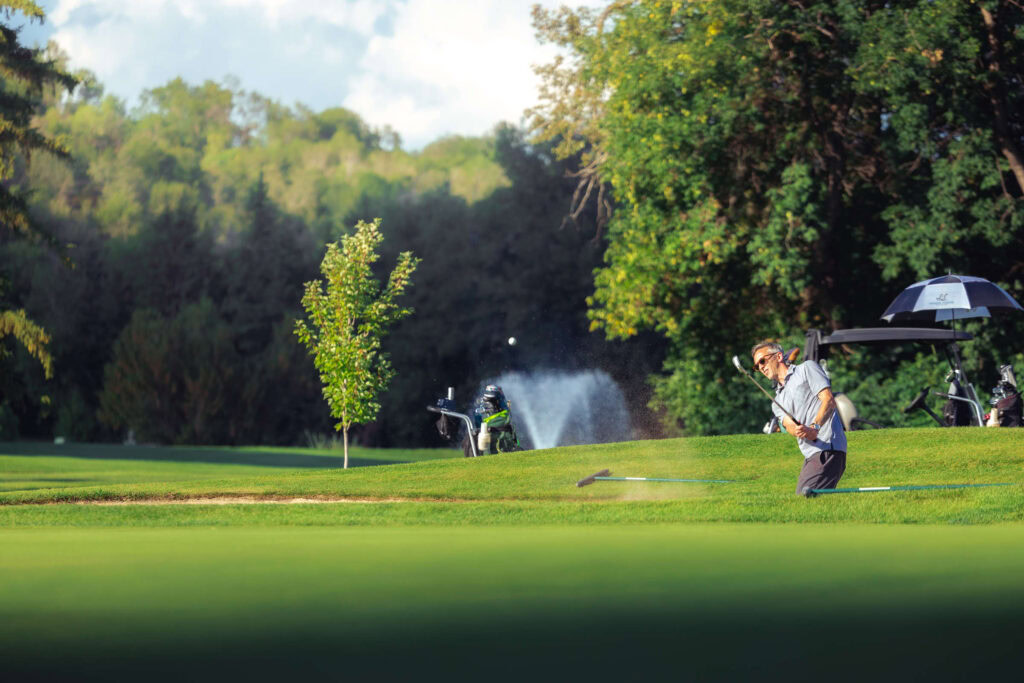 Lush golf course at Highlands Golf Club with golfer and trees in background.