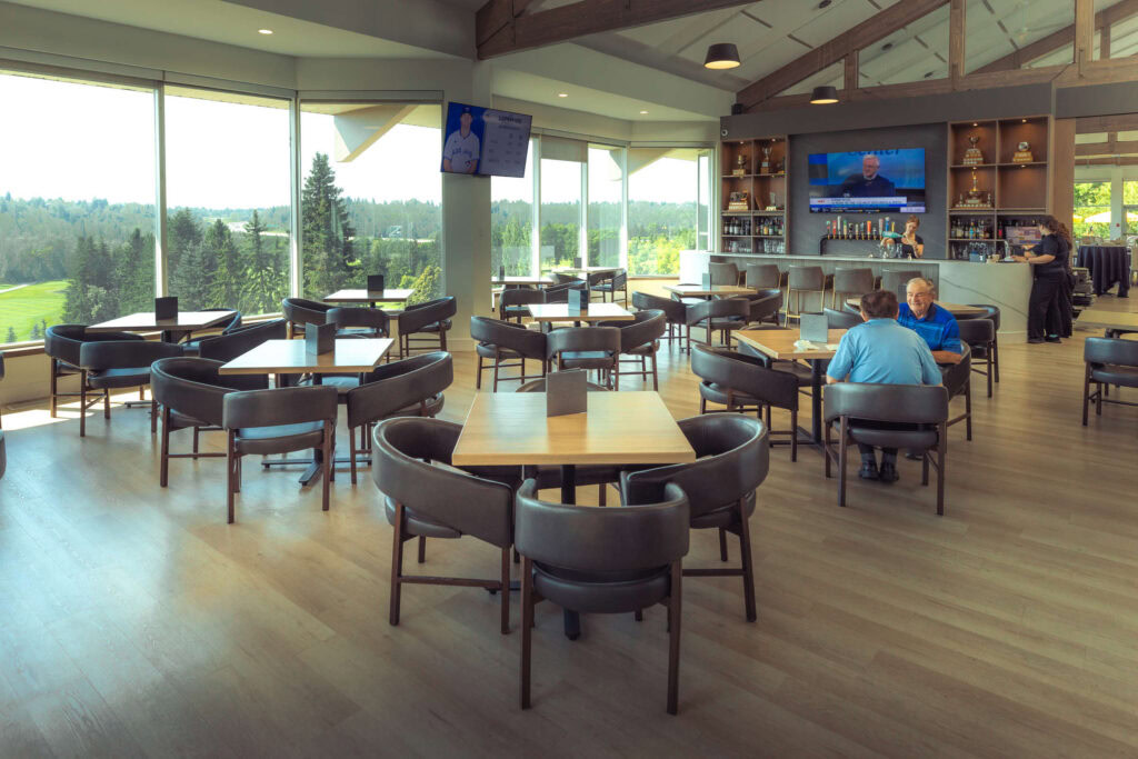 Bright indoor golf clubhouse with panoramic views of the golf course and modern amenities.