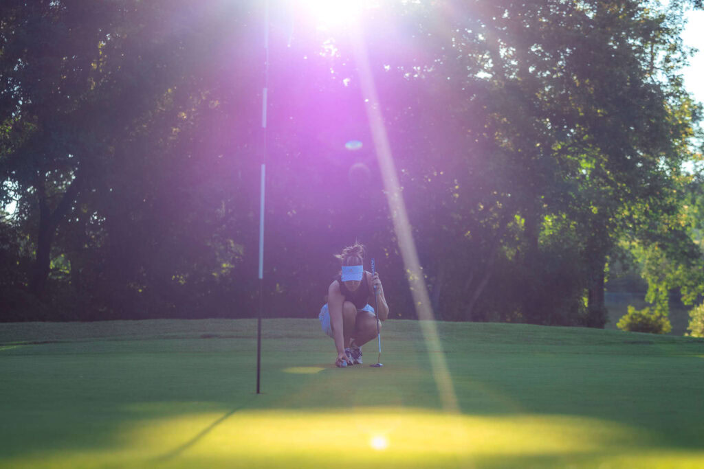 Serene golfer preparing putt on lush green golf course at Highlands Golf Club, CO.