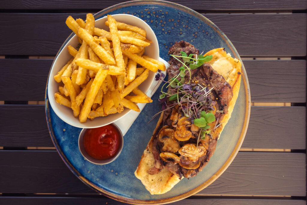Delicious steak sandwich with fries, mushrooms, and microgreens at Highlands Golf Club.