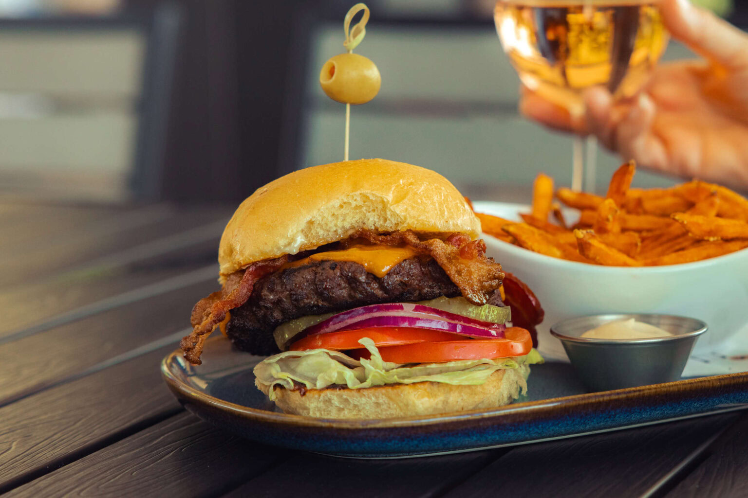 Juicy bacon cheeseburger with fresh vegetables at Highlands Golf Club restaurant.