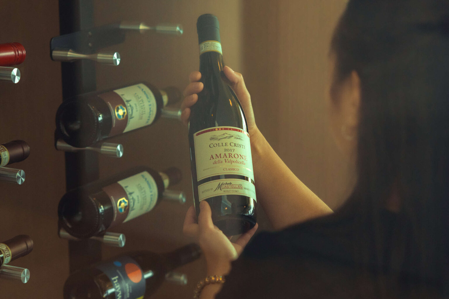 Elegant woman selecting wine at Highlands Golf Club wine cellar.