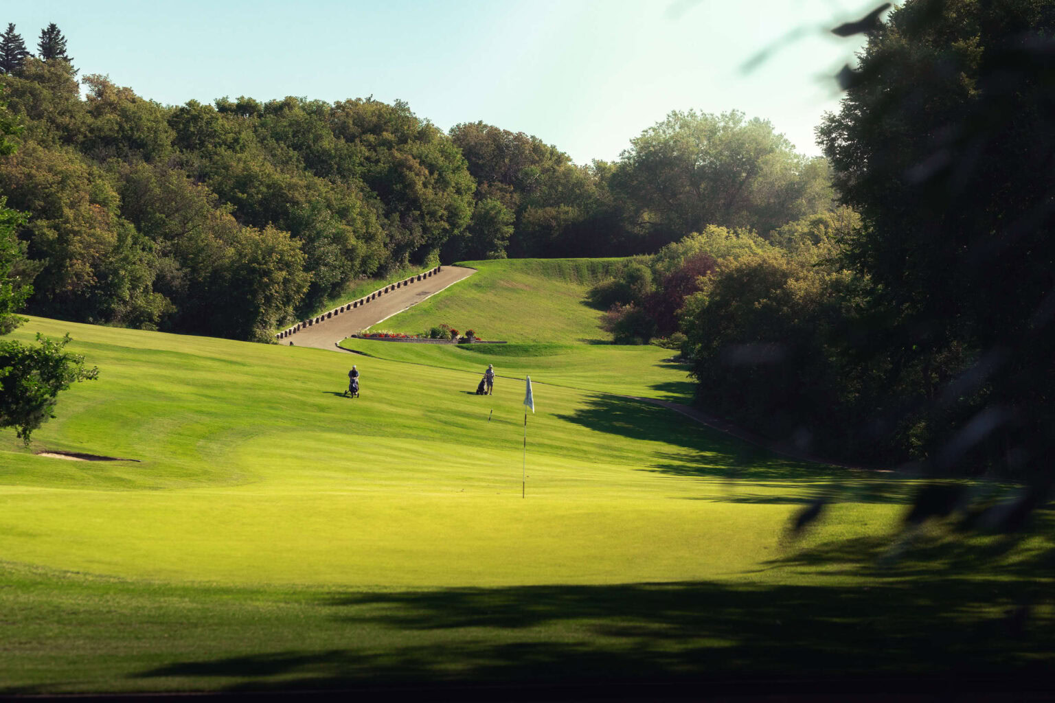 Lush golf course at Highlands Golf Club with players and scenic trees.