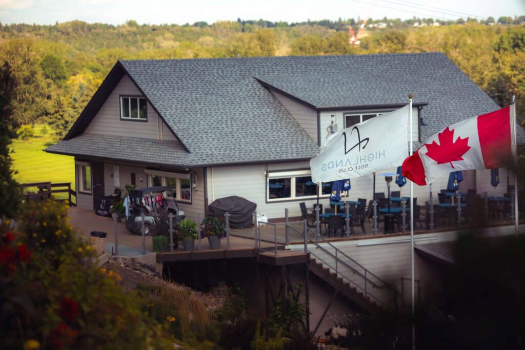 Stunning hillside view of Highlands Golf Club with outdoor patio and Canadian flags.