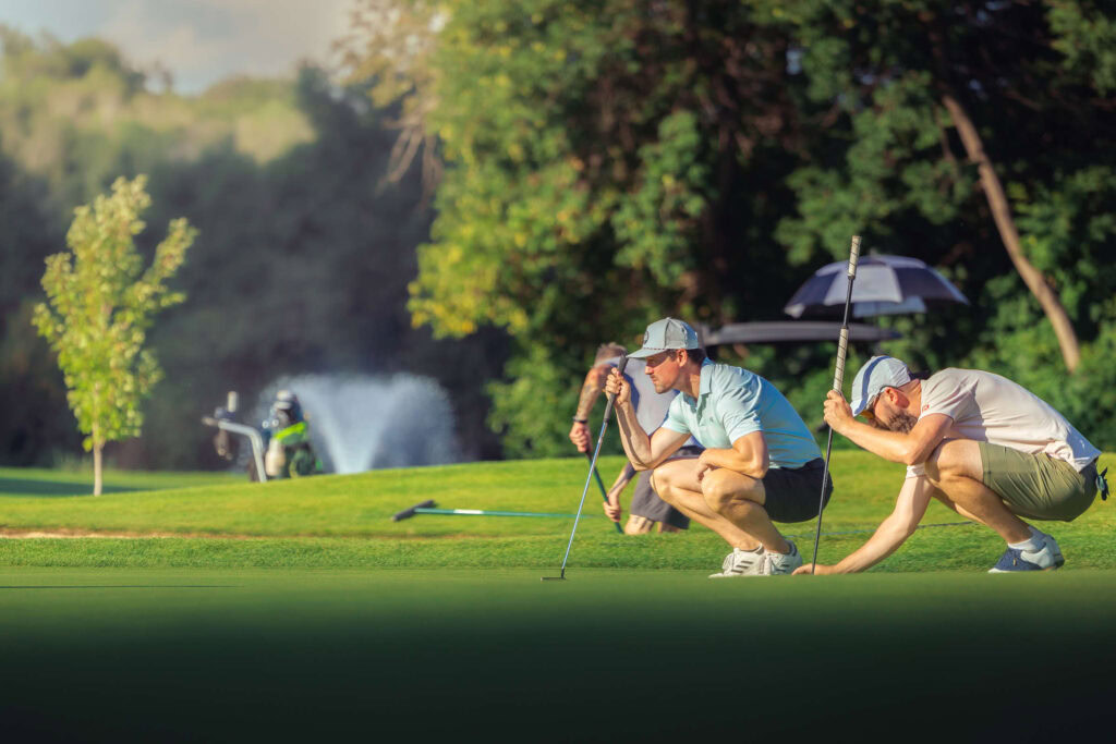Perfect shot of golfers putting on a lush green golf course at Highlands Golf Club.
