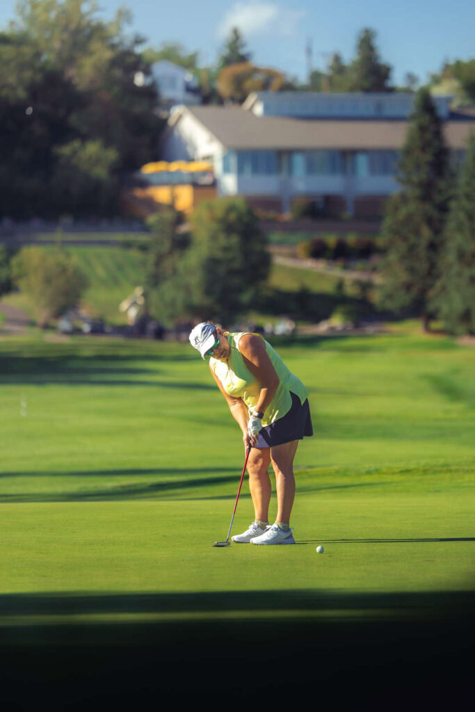 Golf woman putting on scenic Highlands Golf course.