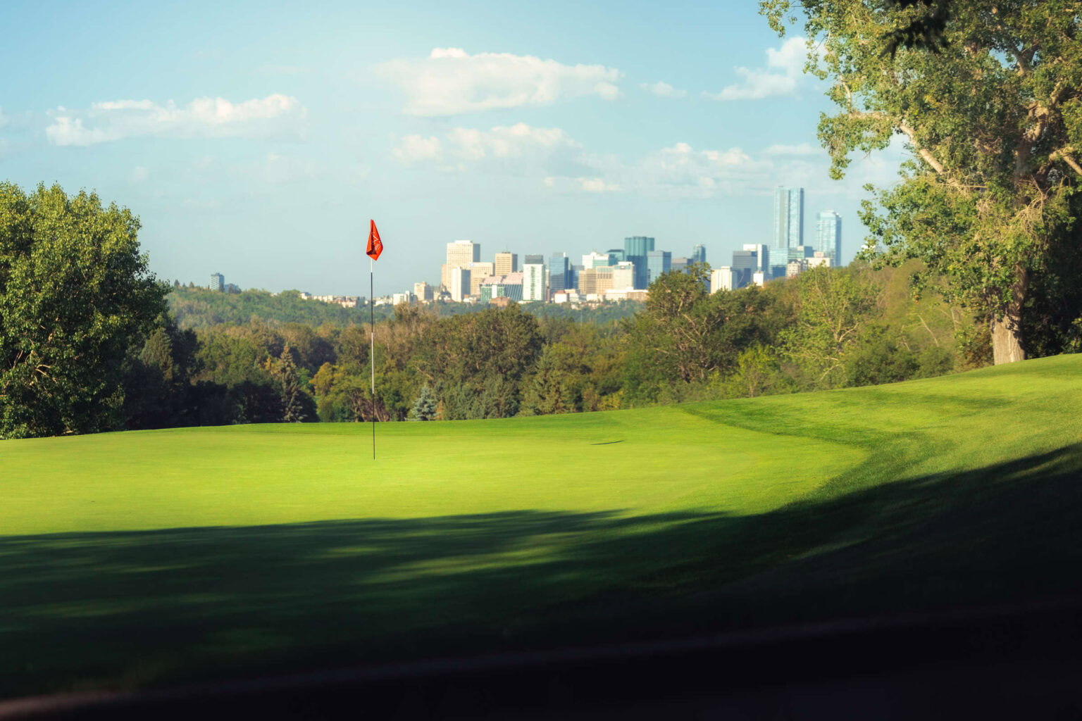 Lush golf course with city skyline view, ideal for golf enthusiasts and scenic sports.